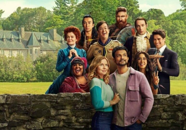 A imagem é um pôster promocional da série Fantasmas (Ghosts). No primeiro plano, vemos Sam (Rose McIver) e Jay (Utkarsh Ambudkar), o casal protagonista, posando diante de um muro de pedra com um grande casarão ao fundo. Atrás deles, um grupo excêntrico de fantasmas de diferentes épocas posa de forma divertida, cada um com trajes característicos de sua época e expressões únicas. O cenário verdejante e a mansão reforçam a ambientação da série, que mistura humor e história de maneira envolvente. A imagem transmite perfeitamente o tom leve e cômico da série.